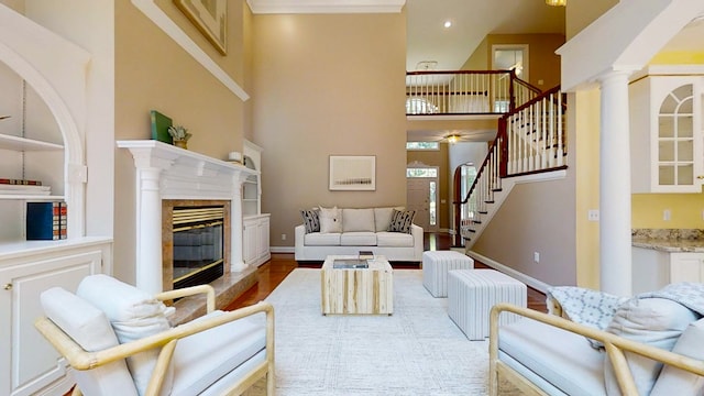 living room featuring ornate columns, wood-type flooring, a high ceiling, and a fireplace