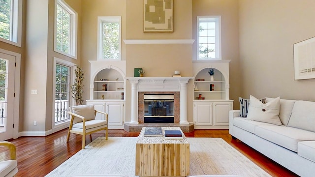 living room with hardwood / wood-style flooring, a premium fireplace, and a towering ceiling