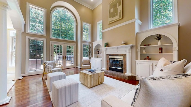 living room featuring a premium fireplace, wood-type flooring, built in features, and french doors