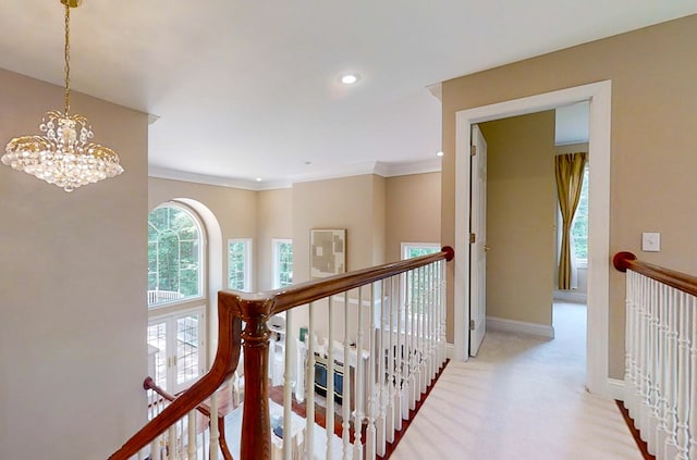 hallway featuring an inviting chandelier, crown molding, and light colored carpet