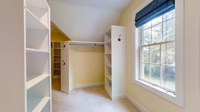 spacious closet with vaulted ceiling and light colored carpet