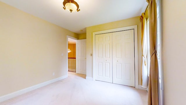 unfurnished bedroom featuring light carpet and a closet