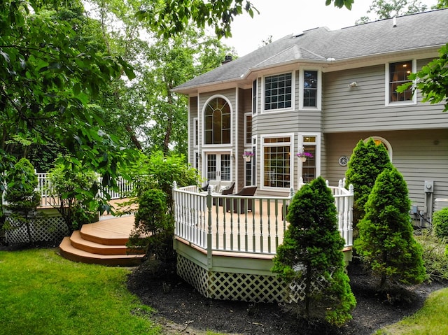 back of property with a wooden deck and a lawn