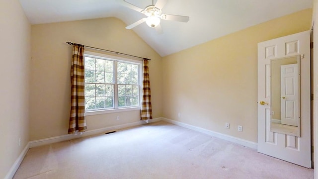 spare room featuring light carpet, lofted ceiling, and ceiling fan