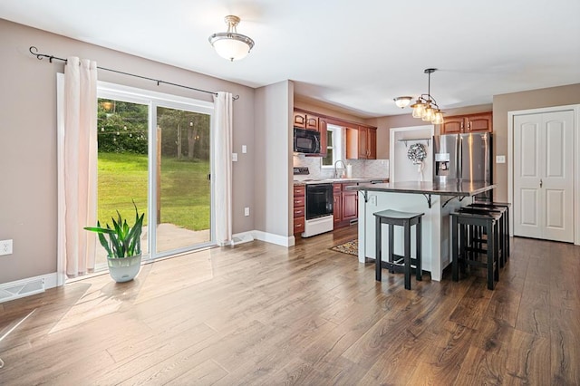 kitchen with stainless steel fridge, backsplash, white electric range, a center island, and a breakfast bar area