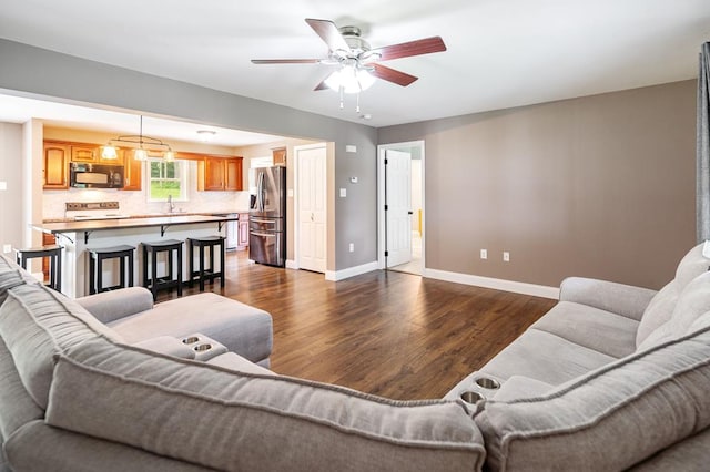 living room with dark hardwood / wood-style floors, ceiling fan, and sink