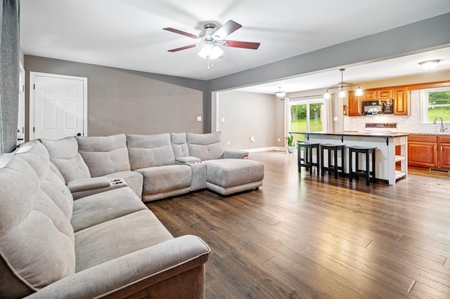 living room with sink, dark hardwood / wood-style flooring, a wealth of natural light, and ceiling fan