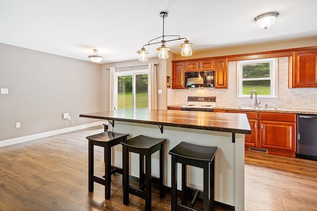 kitchen with sink, wood counters, tasteful backsplash, a kitchen island, and appliances with stainless steel finishes