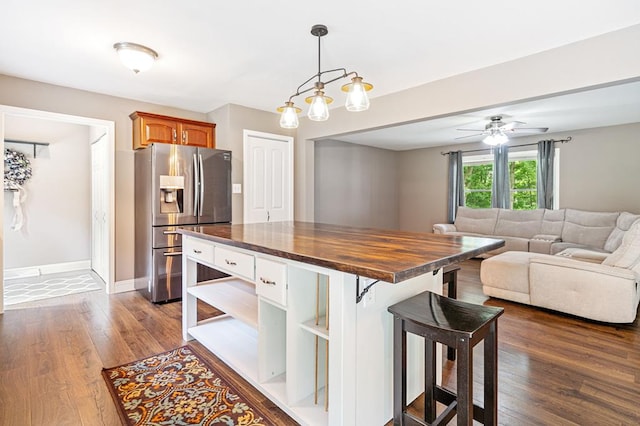 kitchen featuring wooden counters, a kitchen bar, decorative light fixtures, stainless steel fridge with ice dispenser, and dark hardwood / wood-style floors