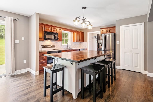 kitchen with a healthy amount of sunlight, a kitchen island, stainless steel fridge with ice dispenser, and range with electric cooktop