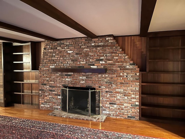 room details featuring a brick fireplace, wooden walls, hardwood / wood-style floors, and beam ceiling