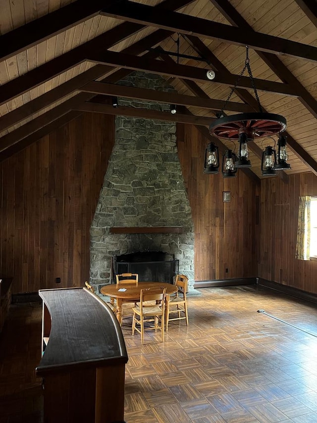 unfurnished living room featuring lofted ceiling with beams, wood ceiling, a fireplace, and wood walls