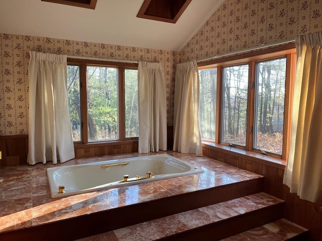 bathroom with plenty of natural light, vaulted ceiling, and a bathtub