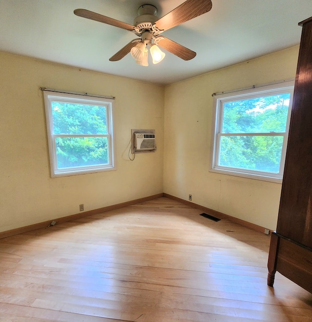 empty room featuring ceiling fan, light wood-type flooring, and an AC wall unit