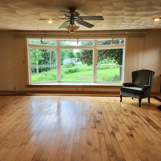 sitting room with ceiling fan, a wealth of natural light, and light hardwood / wood-style flooring