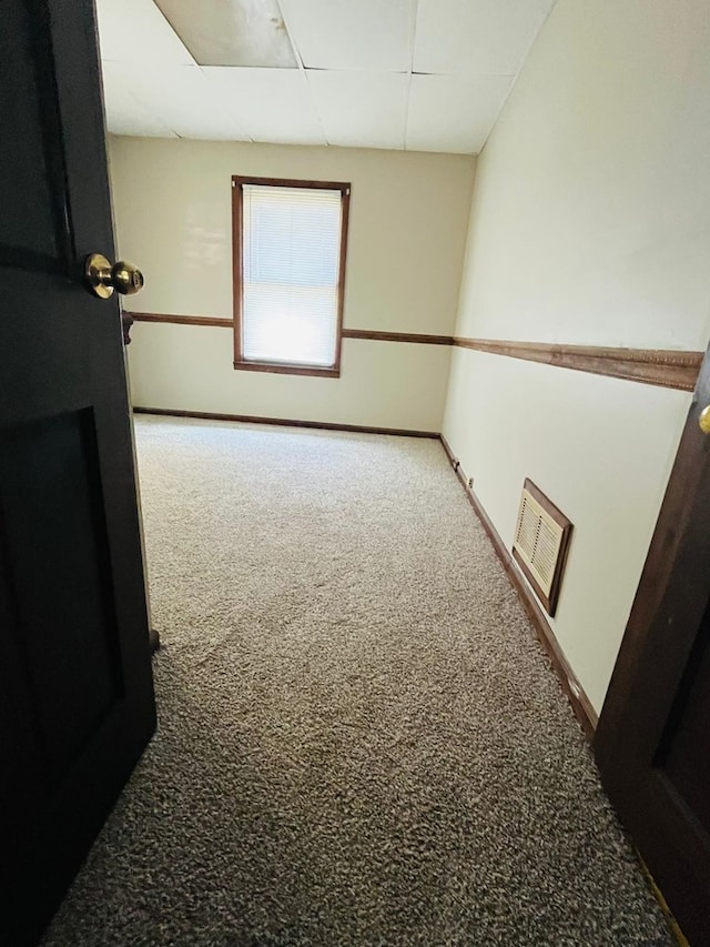 empty room featuring carpet floors and a drop ceiling