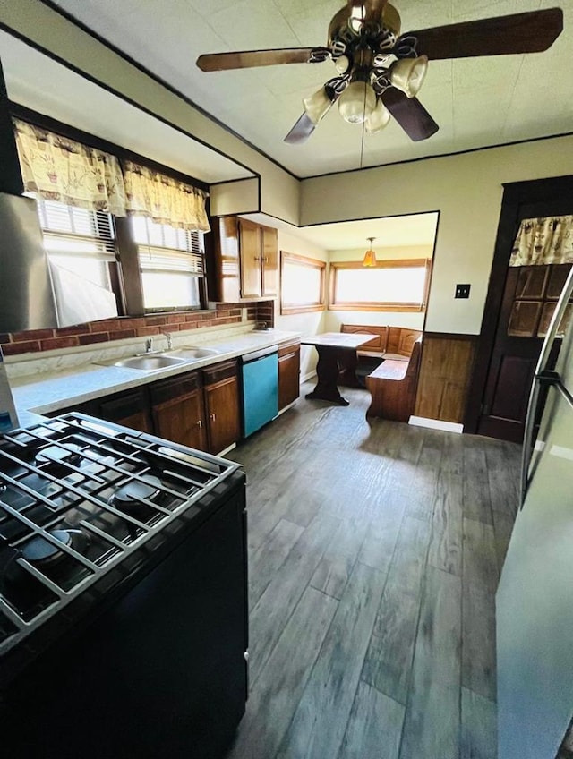 kitchen with black range with electric stovetop, wood walls, sink, stainless steel dishwasher, and dark hardwood / wood-style flooring