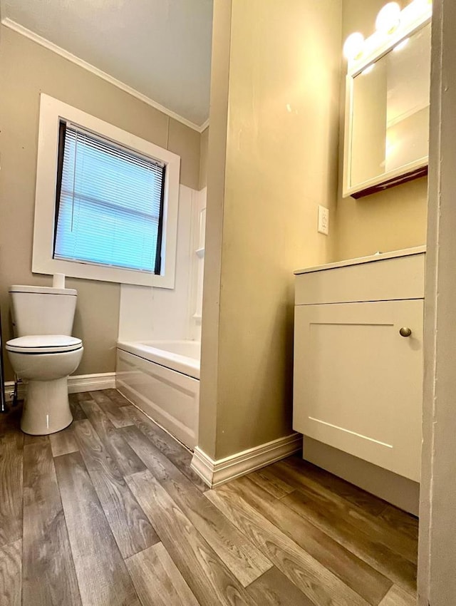 bathroom with a bathtub, hardwood / wood-style flooring, crown molding, and toilet