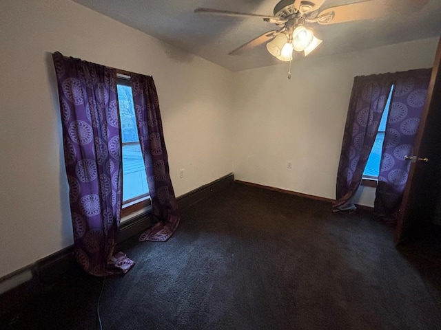 spare room with ceiling fan and dark colored carpet