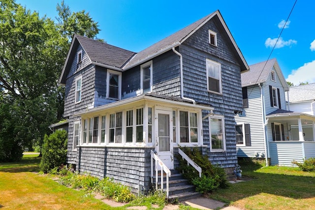 view of front of house with a sunroom and a front yard