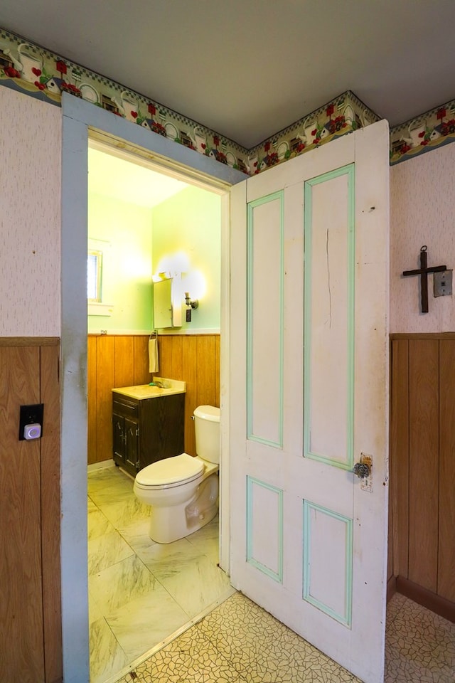 bathroom featuring vanity, toilet, and wooden walls