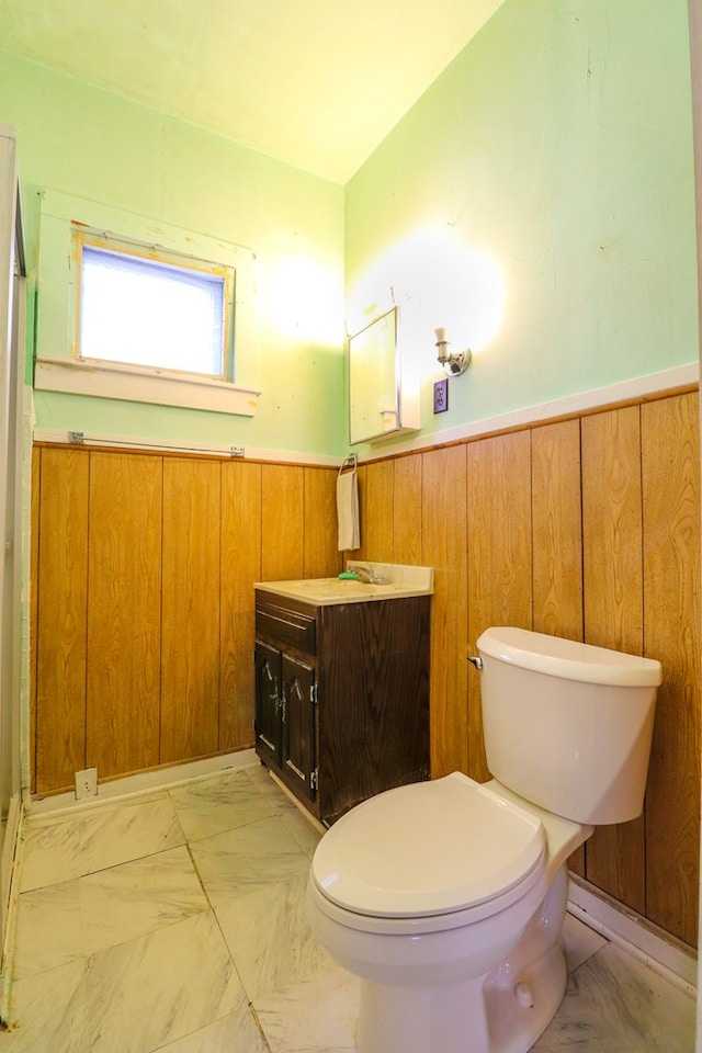 bathroom featuring vanity, toilet, and wood walls