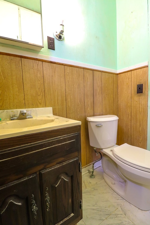 bathroom with wood walls, vanity, and toilet