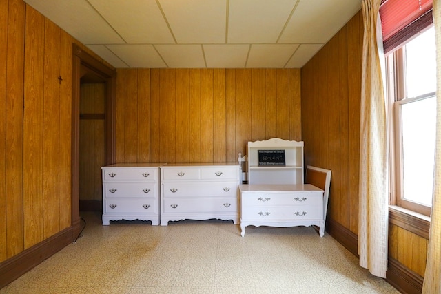 unfurnished bedroom with a drop ceiling and wood walls