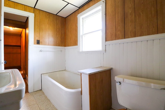 bathroom with wood walls, toilet, and a tub to relax in