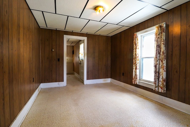 empty room with a wealth of natural light, wooden walls, and a drop ceiling