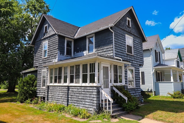 view of front of home with a sunroom and a front yard