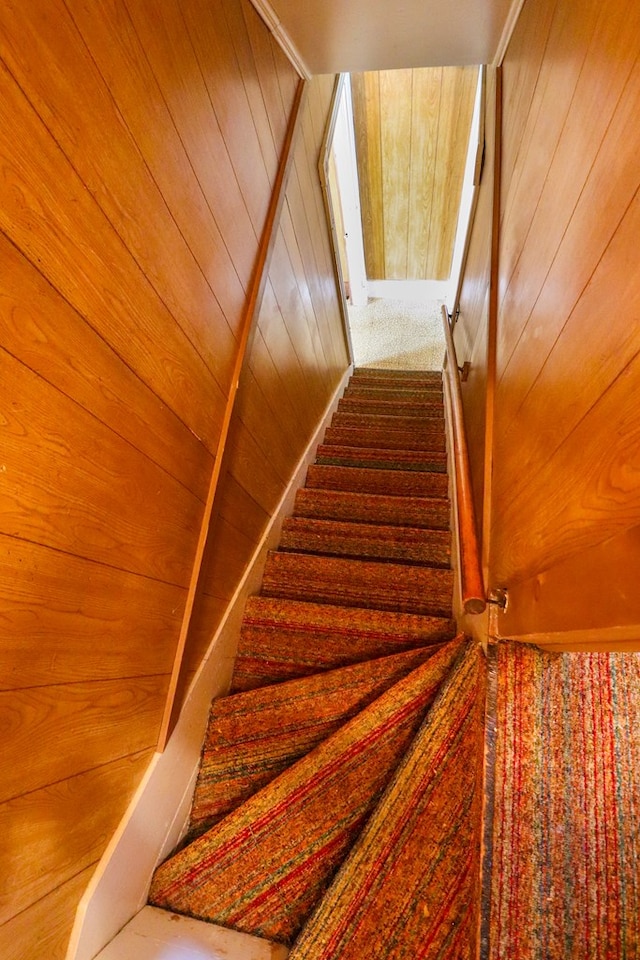 stairway featuring wooden walls