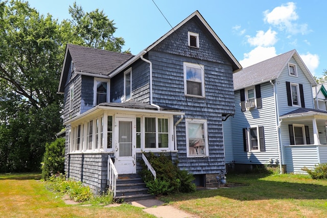 view of front of home with a sunroom and a front lawn