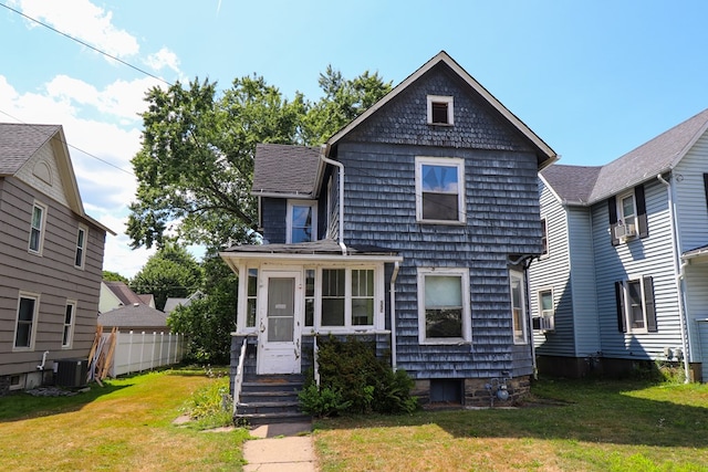 view of front of house with a sunroom, cooling unit, a front yard, and central AC