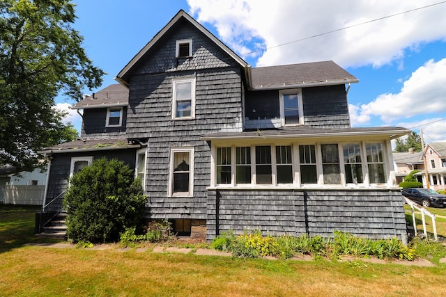 rear view of property with a sunroom and a yard