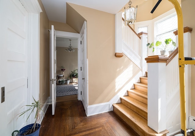 stairs with an inviting chandelier and parquet floors