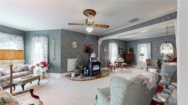 carpeted living room with ceiling fan, crown molding, and a wood stove