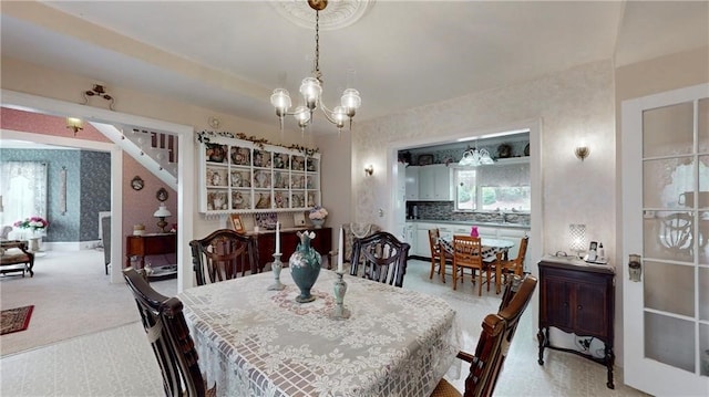 carpeted dining room featuring a notable chandelier