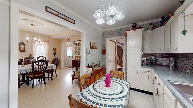 kitchen featuring white cabinets, pendant lighting, sink, a chandelier, and crown molding