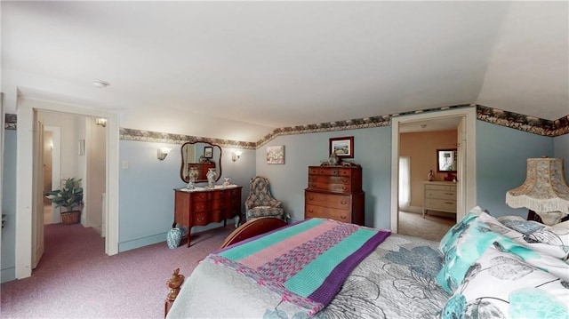 bedroom featuring lofted ceiling, ensuite bath, and light colored carpet