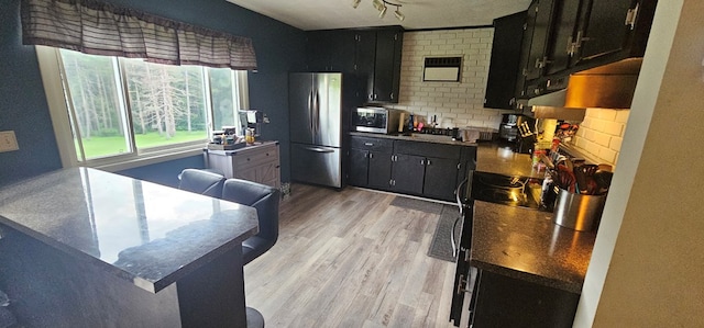 kitchen featuring light hardwood / wood-style floors, backsplash, and appliances with stainless steel finishes