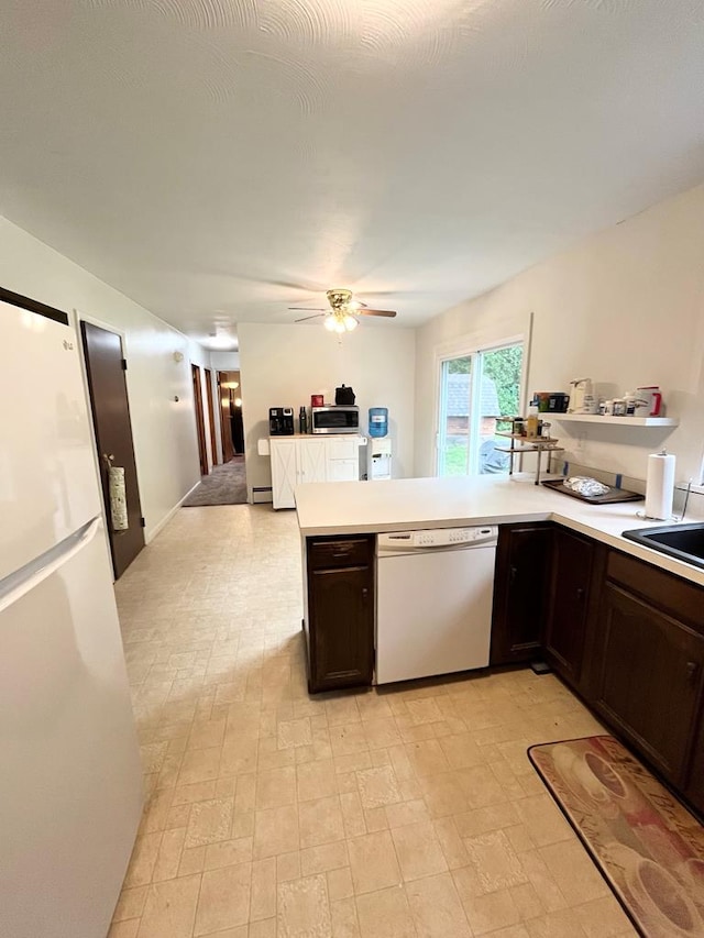 kitchen with white appliances, dark brown cabinets, kitchen peninsula, and ceiling fan