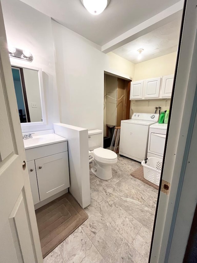 bathroom featuring toilet, sink, and washing machine and dryer