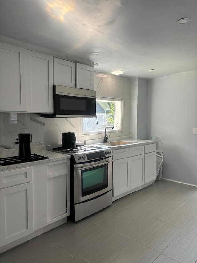 kitchen featuring appliances with stainless steel finishes, white cabinets, sink, and backsplash