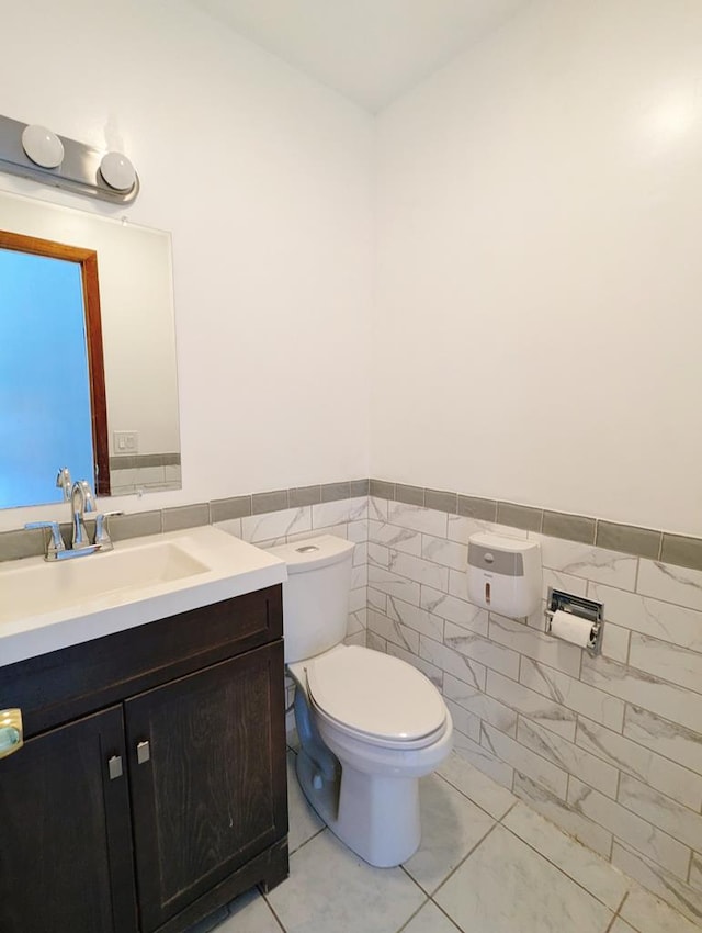 bathroom with vanity, tile walls, and toilet