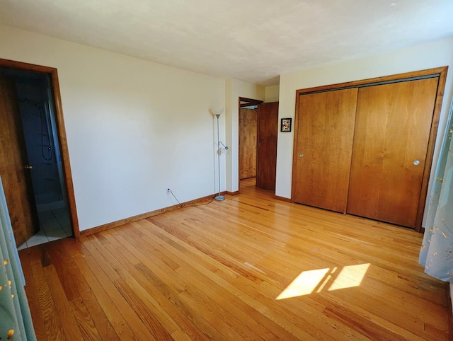 unfurnished bedroom with light hardwood / wood-style flooring, a closet, and ensuite bathroom