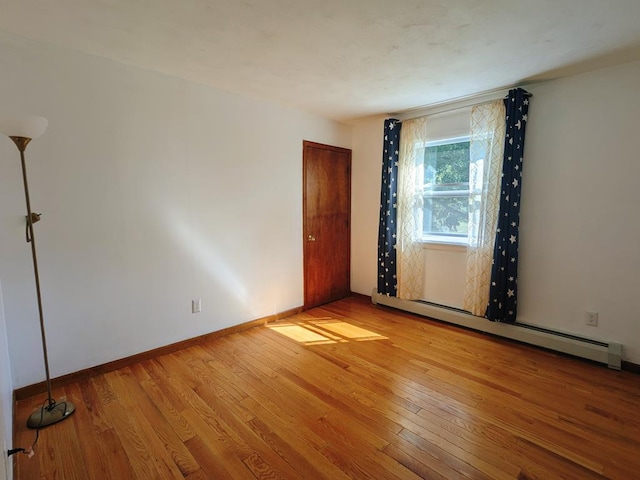 spare room featuring a baseboard radiator and light hardwood / wood-style floors