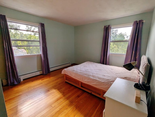 bedroom with light hardwood / wood-style flooring, multiple windows, and a baseboard radiator