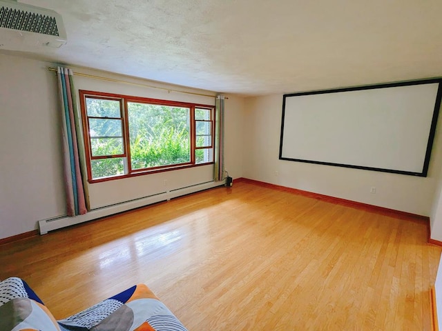 home theater room with light hardwood / wood-style floors and baseboard heating