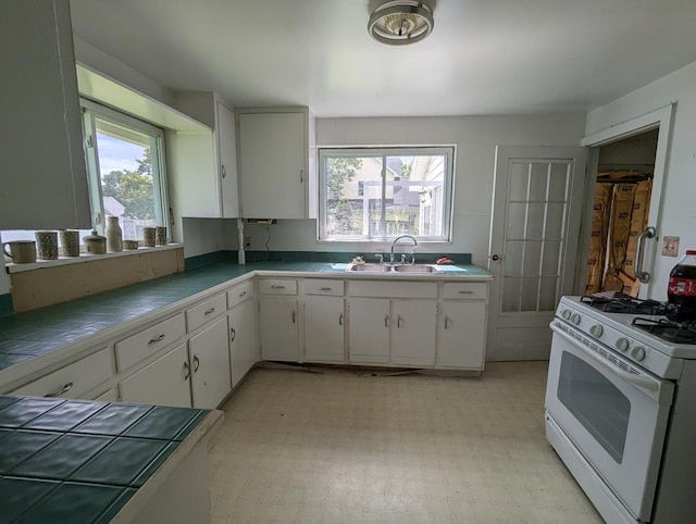 kitchen featuring white cabinetry, sink, tile countertops, and white gas range oven